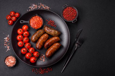 Tuzlu, baharatlı ve otlu sulu sosisler koyu beton arka planda kızartılıyor.
