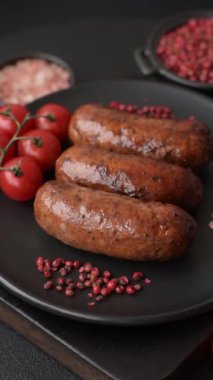 Tuzlu, baharatlı ve otlu sulu sosisler koyu beton arka planda kızartılıyor.