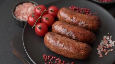 Tuzlu, baharatlı ve otlu sulu sosisler koyu beton arka planda kızartılıyor.