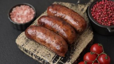 Tuzlu, baharatlı ve otlu sulu sosisler koyu beton arka planda kızartılıyor.