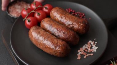 Tuzlu, baharatlı ve otlu sulu sosisler koyu beton arka planda kızartılıyor.