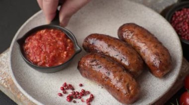 Tuzlu, baharatlı ve otlu sulu sosisler koyu beton arka planda kızartılıyor.