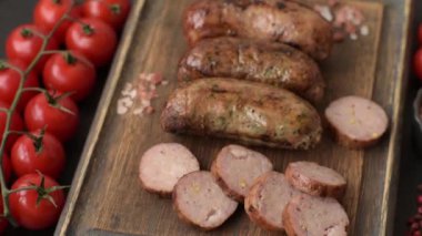 Tuzlu, baharatlı ve otlu sulu sosisler koyu beton arka planda kızartılıyor.
