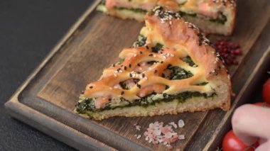 Somon, ıspanak ya da brokoli, tuz ve baharatlı kiş parçaları koyu beton arka planda.