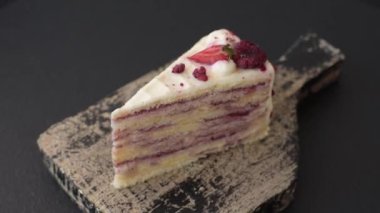 Üzerinde beyaz krema, ahududu ve çilek olan bir dilim tatlı katmanlı pasta.