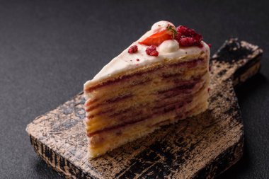 Üzerinde beyaz krema, ahududu ve çilek olan bir dilim tatlı katmanlı pasta.