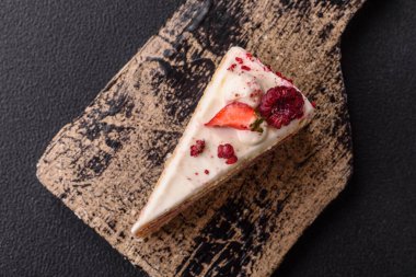 Üzerinde beyaz krema, ahududu ve çilek olan bir dilim tatlı katmanlı pasta.