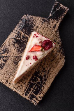 Üzerinde beyaz krema, ahududu ve çilek olan bir dilim tatlı katmanlı pasta.