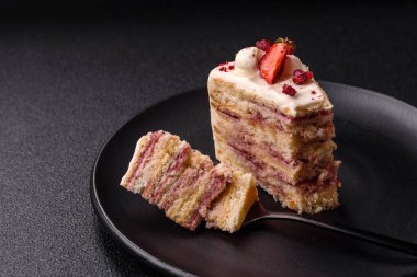 Üzerinde beyaz krema, ahududu ve çilek olan bir dilim tatlı katmanlı pasta.