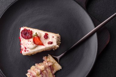 Üzerinde beyaz krema, ahududu ve çilek olan bir dilim tatlı katmanlı pasta.