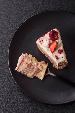 Üzerinde beyaz krema, ahududu ve çilek olan bir dilim tatlı katmanlı pasta.