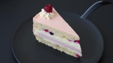 Bir parça tatlı kek pembe kremalı ahududu aromalı, kurabiyeli, peynirli kek koyu betondan arka planda.
