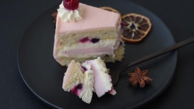 Bir parça tatlı kek pembe kremalı ahududu aromalı, kurabiyeli, peynirli kek koyu betondan arka planda.