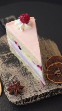 Bir parça tatlı kek pembe kremalı ahududu aromalı, kurabiyeli, peynirli kek koyu betondan arka planda.