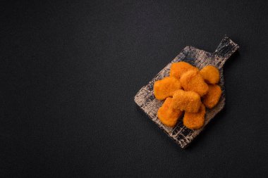 Delicious fresh crispy chicken nuggets on a dark concrete background. Unhealthy food, fast food