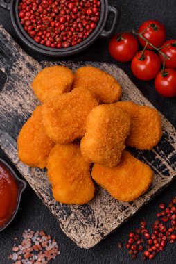 Delicious fresh crispy chicken nuggets on a dark concrete background. Unhealthy food, fast food