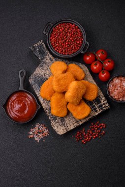 Delicious fresh crispy chicken nuggets on a dark concrete background. Unhealthy food, fast food