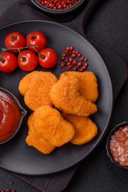 Delicious fresh crispy chicken nuggets on a dark concrete background. Unhealthy food, fast food