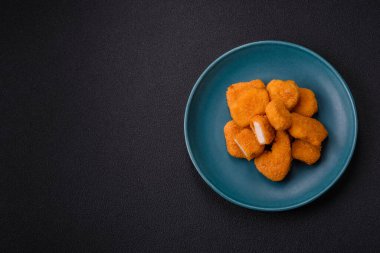Delicious fresh crispy chicken nuggets on a dark concrete background. Unhealthy food, fast food
