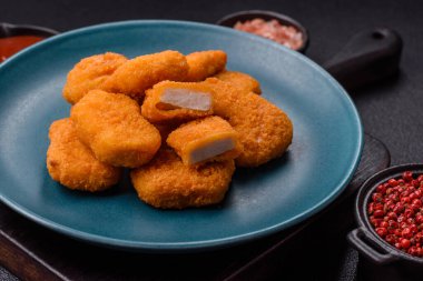 Delicious fresh crispy chicken nuggets on a dark concrete background. Unhealthy food, fast food