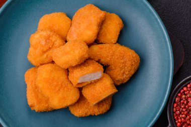 Delicious fresh crispy chicken nuggets on a dark concrete background. Unhealthy food, fast food