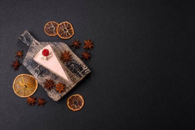 Bir parça tatlı kek pembe kremalı ahududu aromalı, kurabiyeli, peynirli kek koyu betondan arka planda.