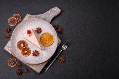 Bir parça tatlı kek pembe kremalı ahududu aromalı, kurabiyeli, peynirli kek koyu betondan arka planda.