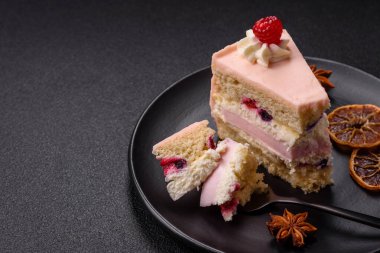 Bir parça tatlı kek pembe kremalı ahududu aromalı, kurabiyeli, peynirli kek koyu betondan arka planda.