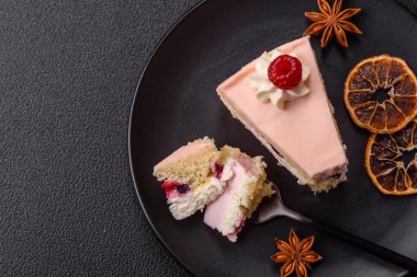 Bir parça tatlı kek pembe kremalı ahududu aromalı, kurabiyeli, peynirli kek koyu betondan arka planda.