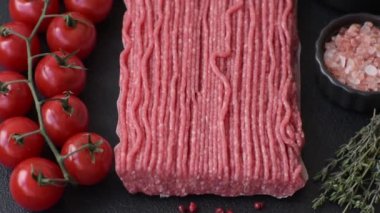 Tuzlu, baharatlı, otlu ve domatesli, koyu beton arkaplanlı çiğ et veya domuz eti.