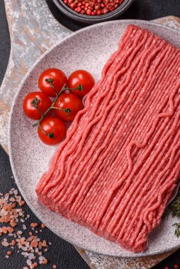 Tuzlu, baharatlı, otlu ve domatesli, koyu beton arkaplanlı çiğ et veya domuz eti.