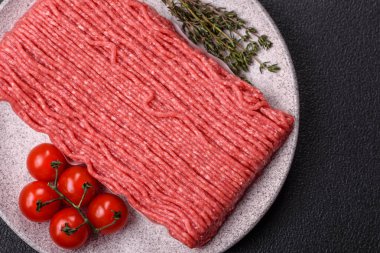 Tuzlu, baharatlı, otlu ve domatesli, koyu beton arkaplanlı çiğ et veya domuz eti.