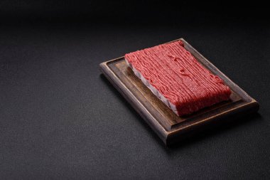 Tuzlu, baharatlı, otlu ve domatesli, koyu beton arkaplanlı çiğ et veya domuz eti.