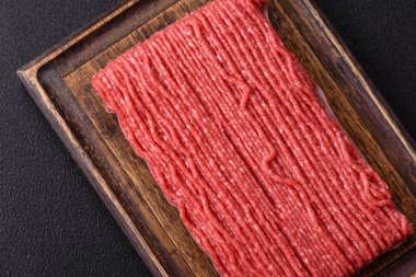 Tuzlu, baharatlı, otlu ve domatesli, koyu beton arkaplanlı çiğ et veya domuz eti.