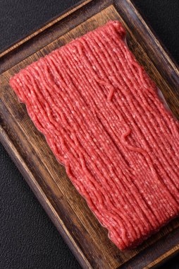 Tuzlu, baharatlı, otlu ve domatesli, koyu beton arkaplanlı çiğ et veya domuz eti.