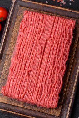 Tuzlu, baharatlı, otlu ve domatesli, koyu beton arkaplanlı çiğ et veya domuz eti.