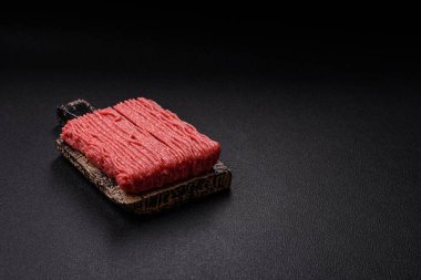 Tuzlu, baharatlı, otlu ve domatesli, koyu beton arkaplanlı çiğ et veya domuz eti.