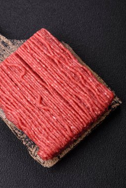 Tuzlu, baharatlı, otlu ve domatesli, koyu beton arkaplanlı çiğ et veya domuz eti.