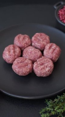 Çiğ et köftesi, domuz eti ya da tuzlu tavuk, baharat ve ottan oluşan koyu beton bir arka planda.