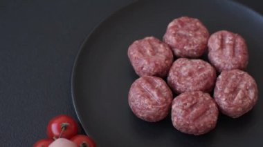 Çiğ et köftesi, domuz eti ya da tuzlu tavuk, baharat ve ottan oluşan koyu beton bir arka planda.