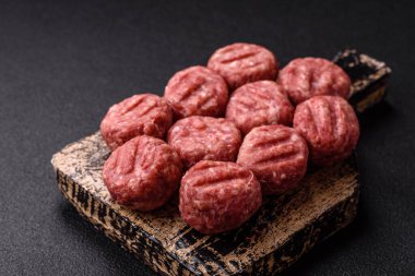 Çiğ et köftesi, domuz eti ya da tuzlu tavuk, baharat ve ottan oluşan koyu beton bir arka planda.