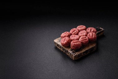 Çiğ et köftesi, domuz eti ya da tuzlu tavuk, baharat ve ottan oluşan koyu beton bir arka planda.