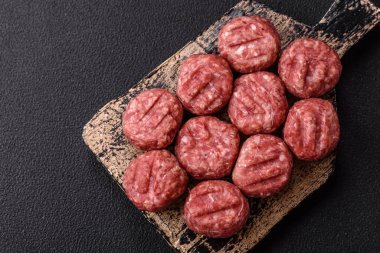 Çiğ et köftesi, domuz eti ya da tuzlu tavuk, baharat ve ottan oluşan koyu beton bir arka planda.