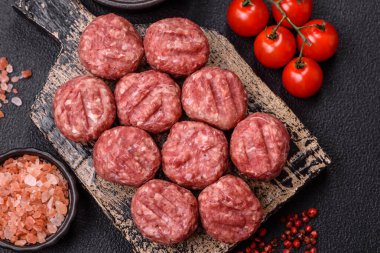 Çiğ et köftesi, domuz eti ya da tuzlu tavuk, baharat ve ottan oluşan koyu beton bir arka planda.