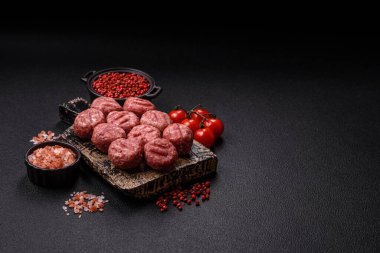 Çiğ et köftesi, domuz eti ya da tuzlu tavuk, baharat ve ottan oluşan koyu beton bir arka planda.