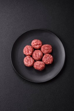 Çiğ et köftesi, domuz eti ya da tuzlu tavuk, baharat ve ottan oluşan koyu beton bir arka planda.