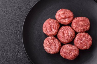 Çiğ et köftesi, domuz eti ya da tuzlu tavuk, baharat ve ottan oluşan koyu beton bir arka planda.