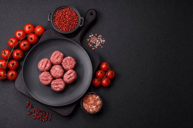 Çiğ et köftesi, domuz eti ya da tuzlu tavuk, baharat ve ottan oluşan koyu beton bir arka planda.