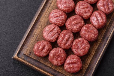 Çiğ et köftesi, domuz eti ya da tuzlu tavuk, baharat ve ottan oluşan koyu beton bir arka planda.