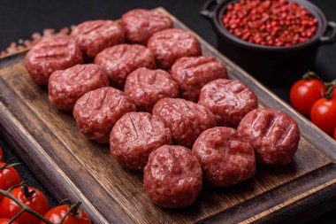 Çiğ et köftesi, domuz eti ya da tuzlu tavuk, baharat ve ottan oluşan koyu beton bir arka planda.